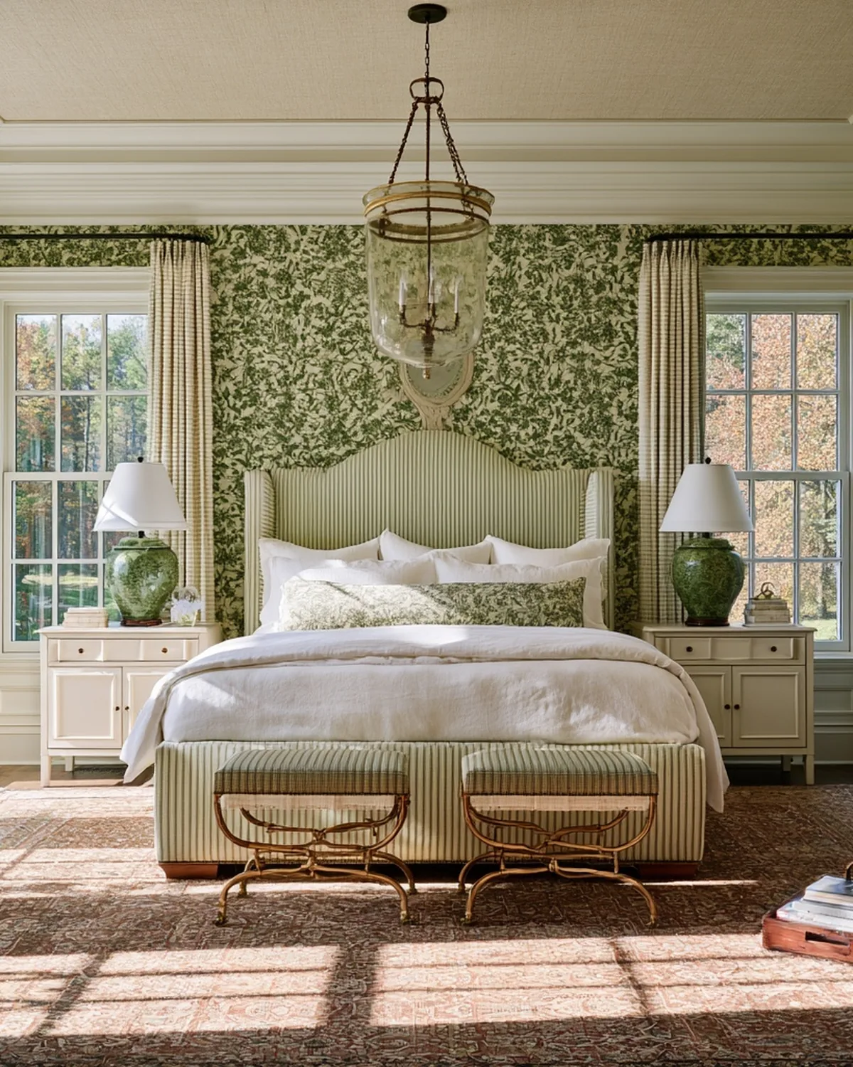 Bedroom with patterned wallpaper, upholstered bed and layered bedding